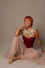 Load image into Gallery viewer, Woman wearing the Bordeaux Étoile Couture Gown featuring a structured Bordeaux corset, flowing champagne skirt, matching chiffon head scarf, and elegant floor-length silhouette.