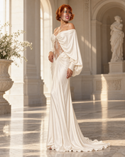 Load image into Gallery viewer, Celeste ivory satin evening gown with off-the-shoulder draping, dramatic long sleeves, sheer floral lace center panel and floor-length silhouette.