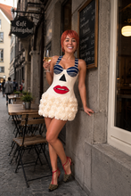 Load image into Gallery viewer, Woman wearing a graphic floral mini dress with three-dimensional white floral appliqués, carrying a black oversized clutch and styled in an editorial luxury fashion look.
