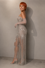 Load image into Gallery viewer, Woman wearing the Celestial Fringe Couture Gown featuring crystal-inspired embroidery, shimmering beaded fringe, a strapless neckline, fitted silhouette, and elegant side slit.
