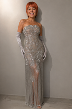 Load image into Gallery viewer, Woman wearing the Celestial Fringe Couture Gown featuring crystal-inspired embroidery, shimmering beaded fringe, a strapless neckline, fitted silhouette, and elegant side slit.