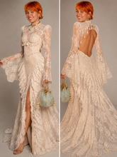 Load image into Gallery viewer, Woman wearing an ivory lace evening gown with high neckline, fitted bodice, tassel embellishments and dramatic long bell sleeves.
