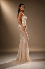 Load image into Gallery viewer, Side view of the Celestia Pearl Gown highlighting its sculpted silhouette, structured peplum waist and elegant floor-length design.
