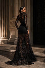 Load image into Gallery viewer, Back view of the Noir Lace Couture Gown showcasing intricate floral lace, sheer back detailing, fitted silhouette, and elegant floor-length train.