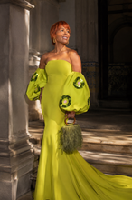 Load image into Gallery viewer, Woman wearing the Lunaria Couture Evening Gown in chartreuse featuring an off-the-shoulder neckline, voluminous sleeves with sequin floral appliqués, a fitted mermaid silhouette, and a floor-length train.