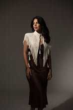 Load image into Gallery viewer, Woman wearing an elegant white embroidered tassel shawl with stand collar and lace-up front paired with a green maxi skirt.