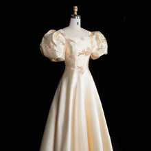 Load image into Gallery viewer, Ivory Regency-inspired formal gown with dramatic puff sleeves, blush floral embroidery, fitted waist and full A-line skirt.