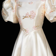 Load image into Gallery viewer, Ivory Regency-inspired formal gown with dramatic puff sleeves, blush floral embroidery, fitted waist and full A-line skirt.