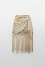 Load image into Gallery viewer, Woman wearing the Nomad Soleil look featuring a handcrafted wooden beaded statement top, embroidered fringe wrap skirt, emerald fold clutch, and elegant resort styling inspired by Mediterranean luxury.
