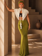 Load image into Gallery viewer, Model wearing the Olive Muse Resort Set featuring an embroidered ivory cape with fringe detailing and a high-waisted olive flared maxi skirt in a Mediterranean-inspired architectural setting.